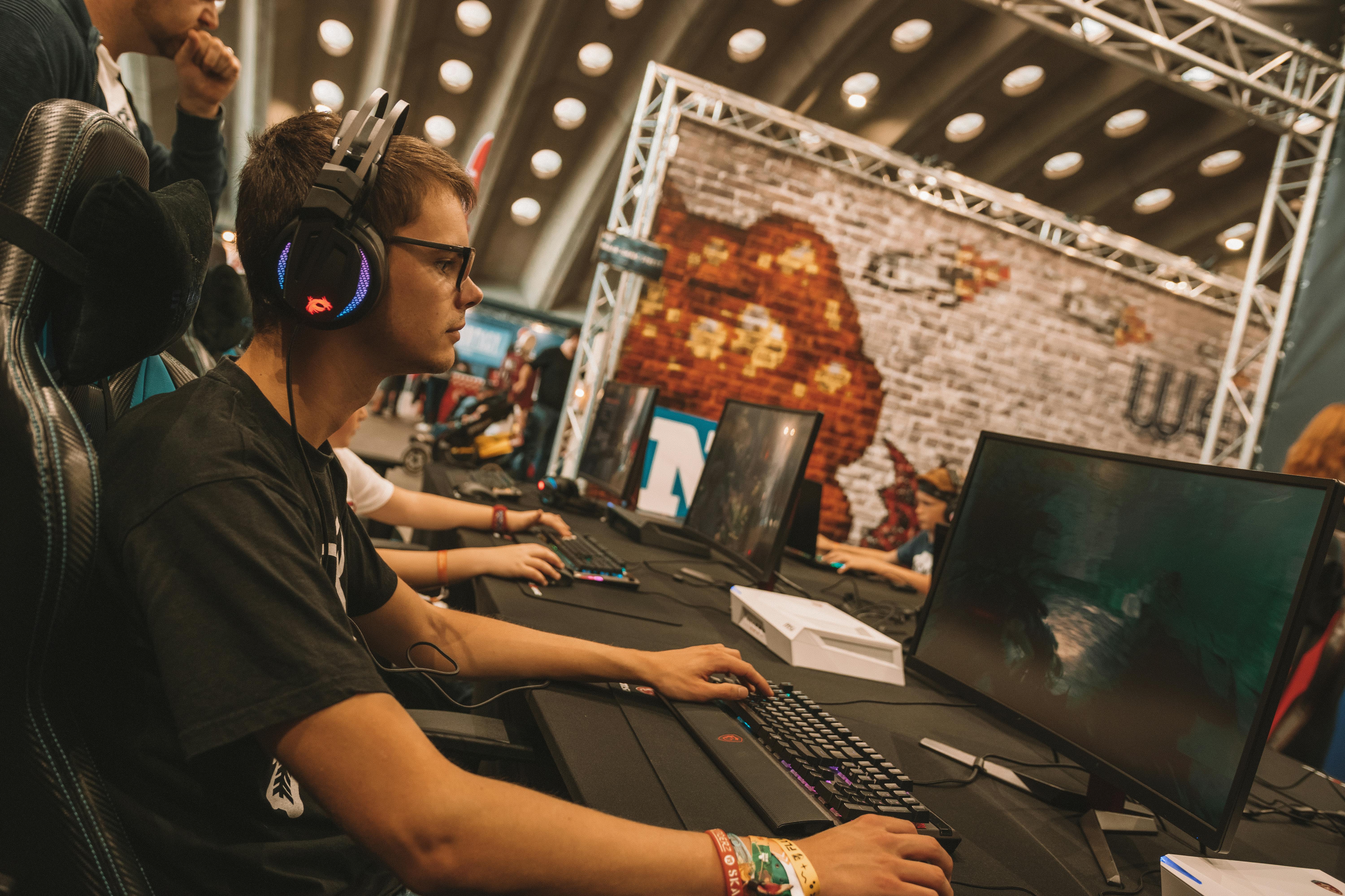 A young male gamer intensely focused during an esports event at an indoor gaming convention.